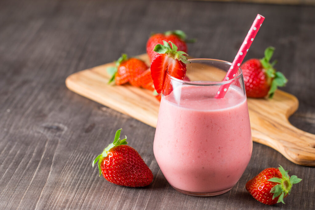 Rosa Smoothie aus Erdbeeren in einem Glas mit Strohhalm. 